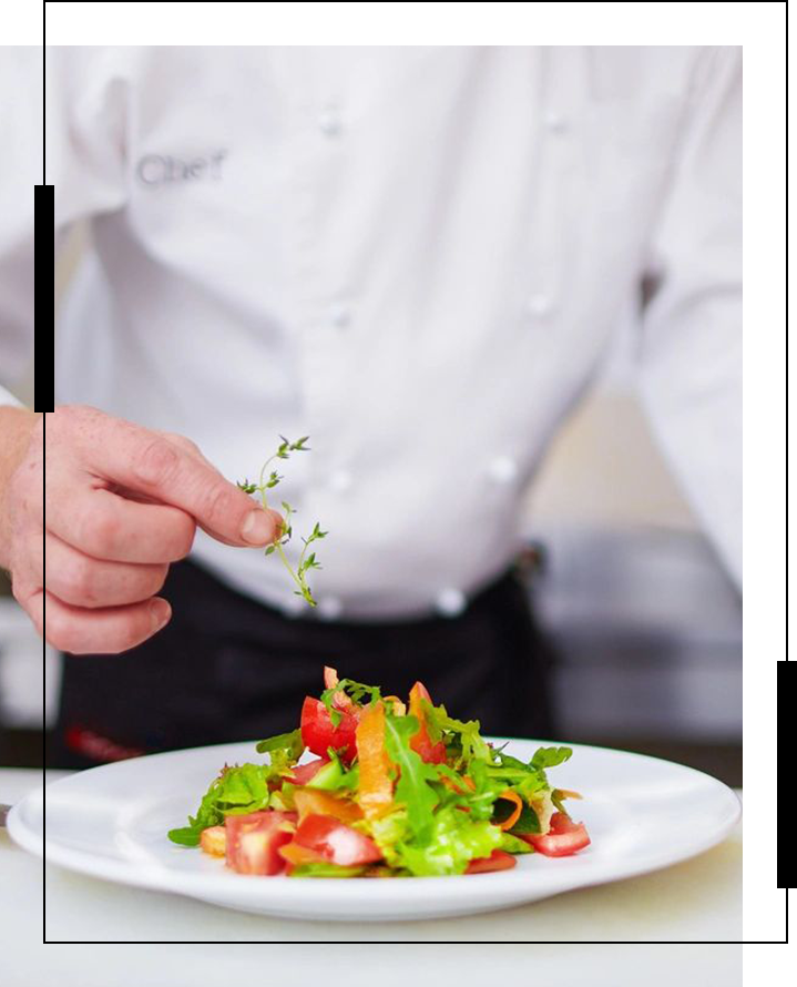 A chef is preparing a salad on top of a plate.